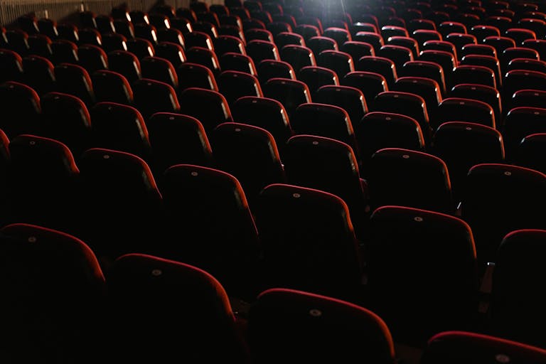 Rows of empty red seats in a dimly lit theater, creating a moody atmosphere.
