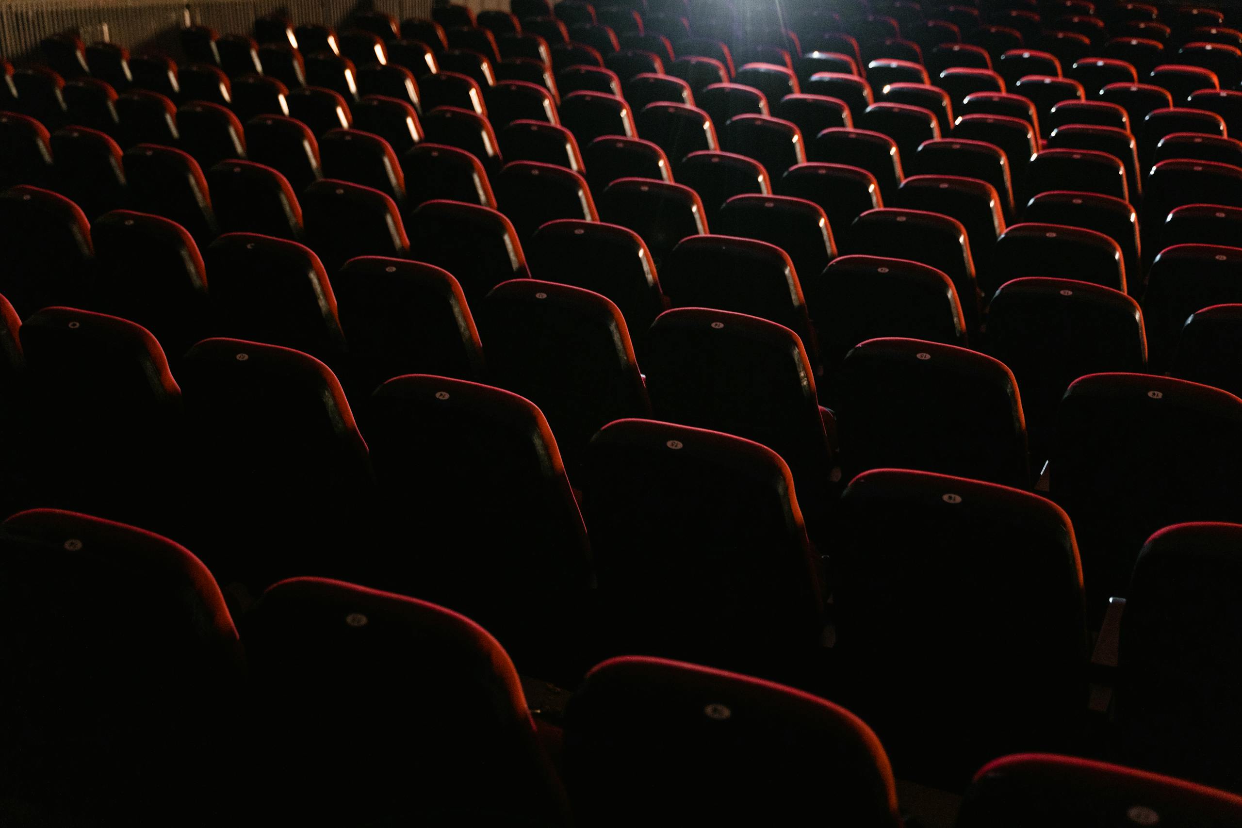 Rows of empty red seats in a dimly lit theater, creating a moody atmosphere.