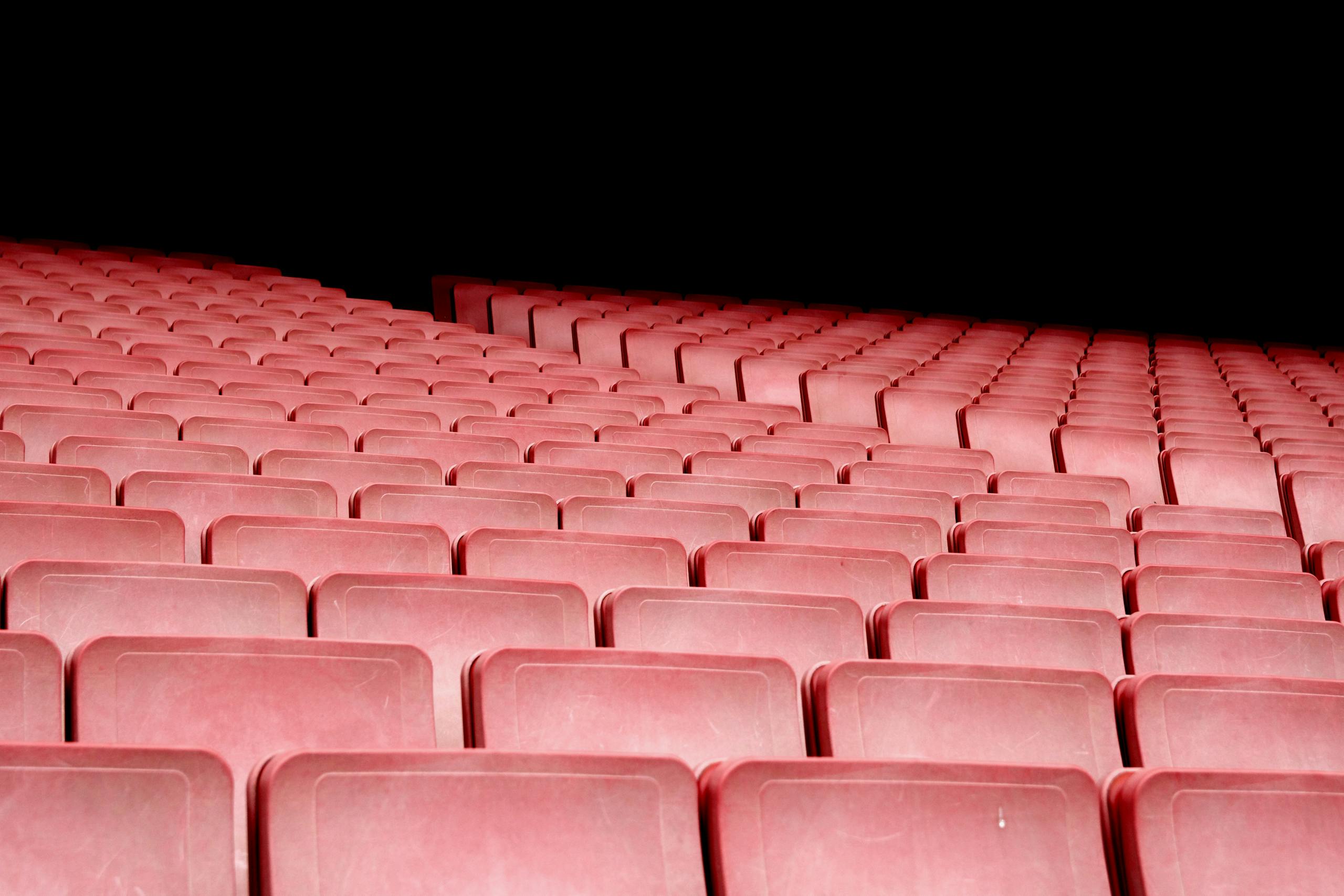 Rows of red seats in an empty auditorium with dramatic lighting.